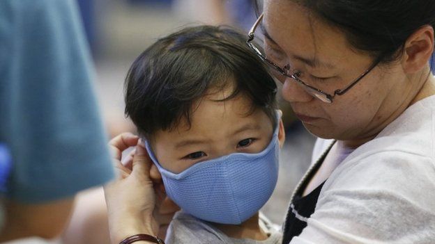 A passenger puts a masks on her son to prevent contracting Middle East Respiratory Syndrome (MERS) at the Incheon International Airport in Incheon, South Korea, June 14, 2015.