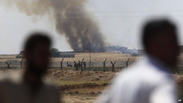 People look from the Turkey-Syria border at smoke rising after a US-led air strike on IS militants in the Syrian town of Tal Abyad (15 June 2015)
