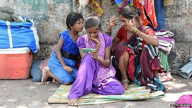 Lady watching video on her smartphone on a pavement in India