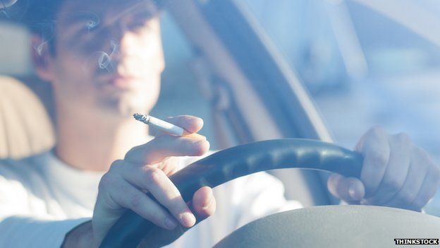 A man smoking in a car