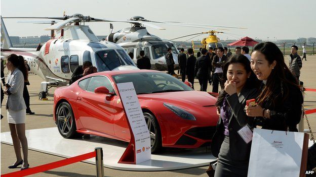 People walk past a Ferrari car and helicopters during the Asian Business Aviation Conference & Exhibition (ABACE2014) at the Shanghai Hongqiao airport in 2014.