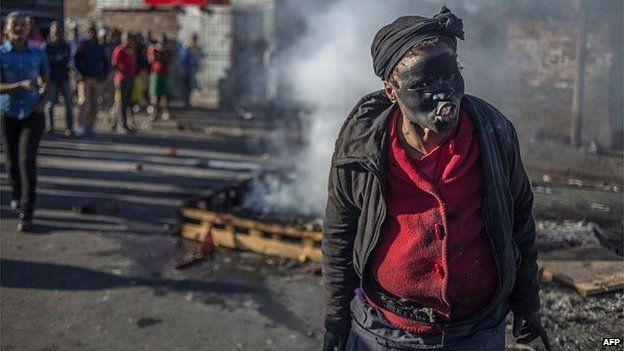 A woman covered in soot gestures and shouts towards foreign nationals outside the Jeppies Hostles, in the Jeppestown area of Johannesburg, on April 17, 2015