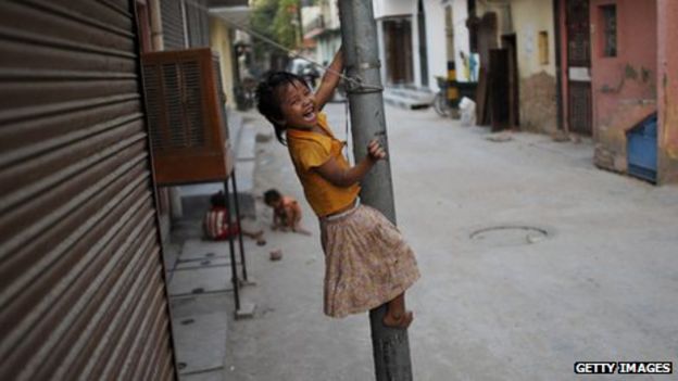 Indian street child climbing lamppost