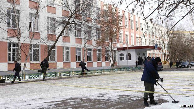 Сотрудник службы безопасности использует мино-металлоискатель, работая возле здания средней школы, где произошел инцидент со стрельбой, на окраине Москвы