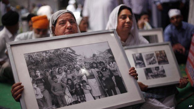 Sikh women hold photographs of riot victims during a protest in Delhi - Credits: BBC