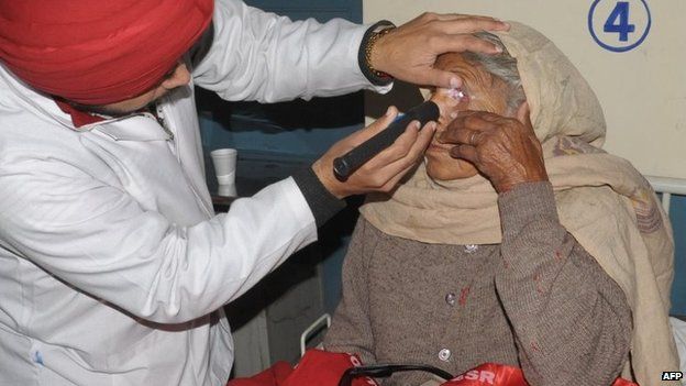 An Indian doctor checks the eye of patient Shinder Kaur, (R), who lost her eyesight after undergoing surgery at an eye camp, at a government hospital in Amritsar on December 5