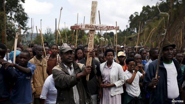 A man holds a cross with writing that reads "death to the president", as he marches with other protesters who are against Burundi President Pierre Nkurunziza and his bid for a third term, towards the town of Ijenda, Burundi, 3 June 2015
