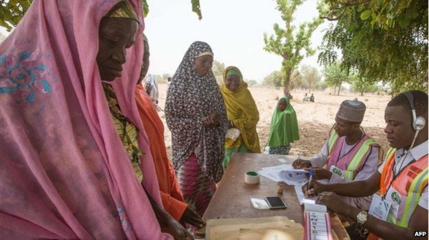 Voters prepare to cast their ballots at a polling station set up under a tree on the outskirt of Kano during the presidential elections, 28 March 2015