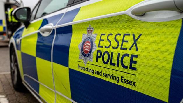 An Essex Police car, with bright yellow and blue wording on it, saying Essex Police, Protecting and serving Essex