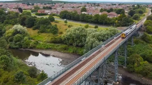 An aerial view of a train running across a viaduct