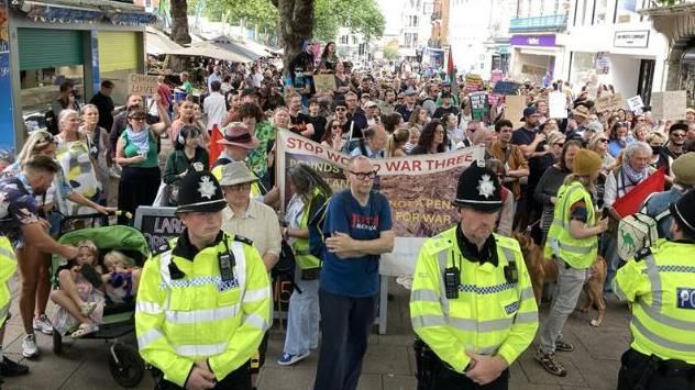 Police officers stand in front of anti-racism protesters