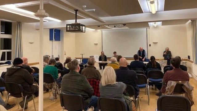 A public meeting about pollution fears in Ironbridge, with more than a dozen people sitting in a hall listening to campigners