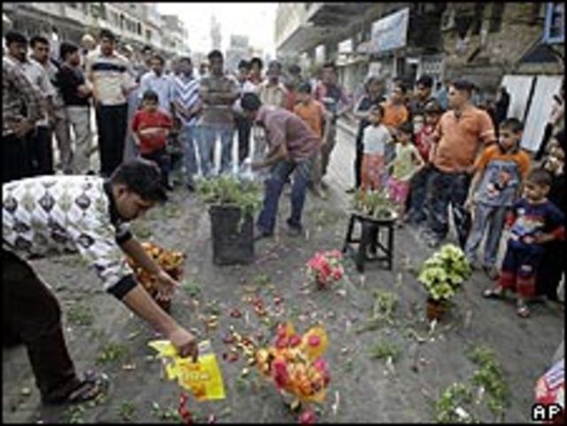 Personas dejando dulces y flores en el escenario de un ataque en Bagdad, 24 abril 2009