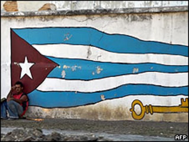 Un trabajador cubano cerca de un mural pintado en una pared de La Habana