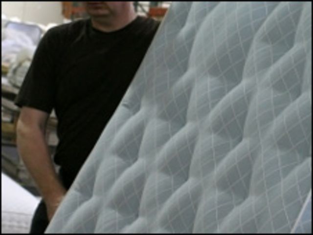 Hombre sosteniendo un colchón (foto de archivo)