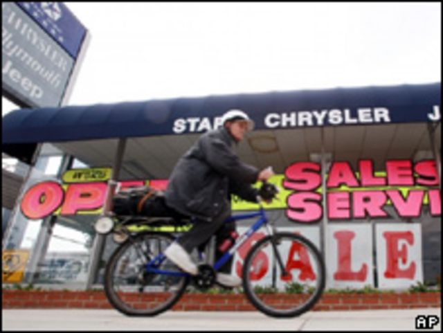 Ciclista pasa delante de concesionaria de Chrysler en venta