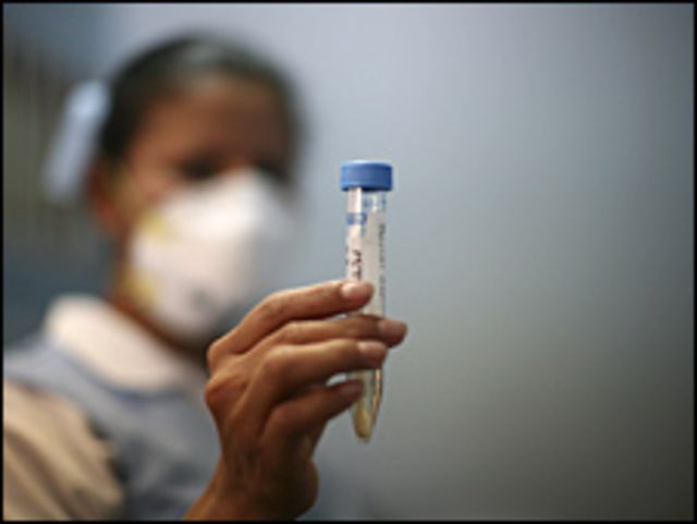 Enfermera con una muestra de gripe porcina en una probeta