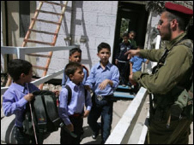 جندي اسرائيلي يوقف تلاميذ فلسطينيين لتفتيش حقائبهم