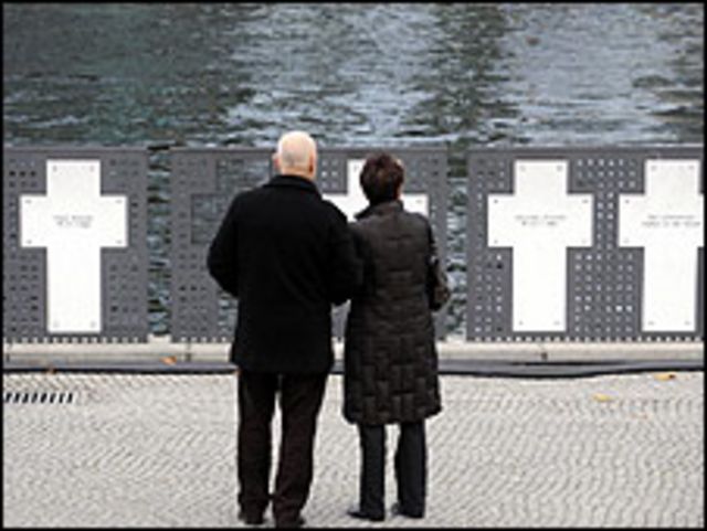 a couple reads the names of east germans who died trying to cross the berlin wall