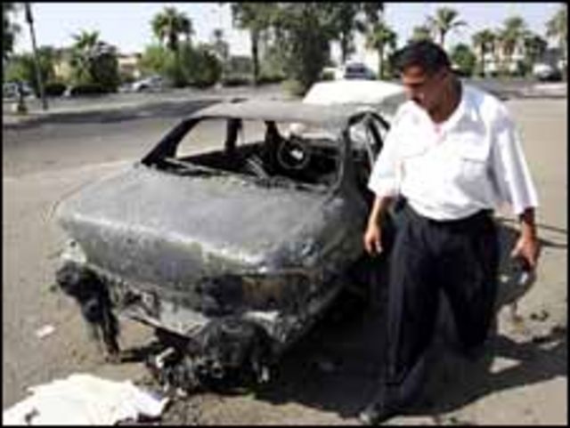 فرد امن عراقي ينظر الى سيارة مدمرة في انفجار