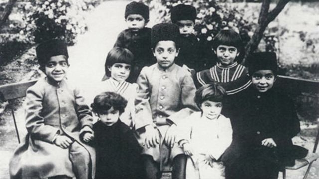 صادق هدایت در پنج سالگی با لباس سفید، همراه با خواهران، برادران و عموزاده‌هایش، در باغ پدربزرگ (نیرالملک)