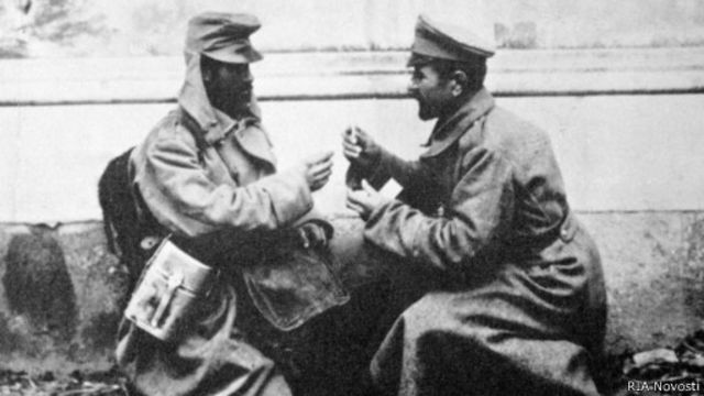 Австрийский (слева) и русский (справа) солдаты обмениваются папиросами во время Первой мировой войны.