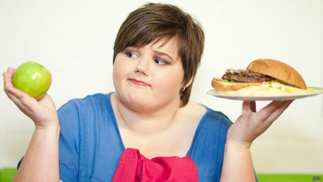Chica decidiendo entre manzana y hamburguesa