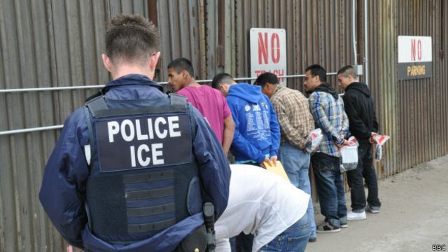 Oficial de migración de EE.UU. con deportados en la valla