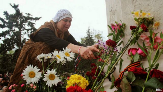 Жінка кладе квіти до стіни Будинку профспілок в Одесі