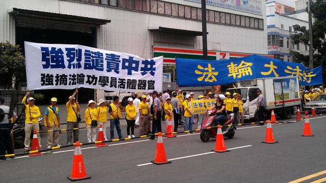 法輪功」抗議團體在一旁默默舉著布條，抗議中共迫害「法輪功」。（BBC中文網駐台灣特約記者嚴思祺攝於新北市）

