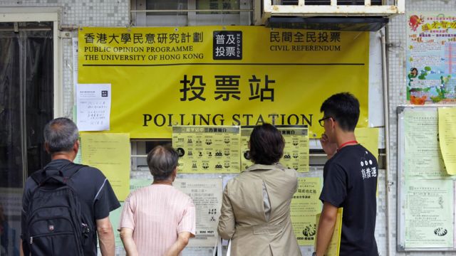 香港新界天水圍市民在「佔領中環」民間全民投票站外閱覽投票介紹(BBC中文網圖片29/6/2014)