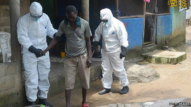 Nurses help an Ebola patient