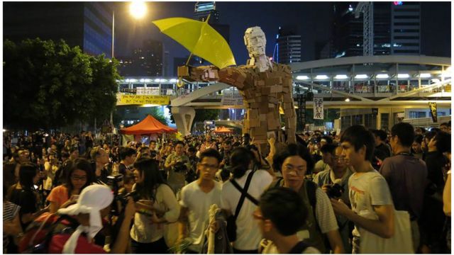 當地時間深夜,一個大型持傘巨人木雕運抵金鐘佔領區,全場雀躍。