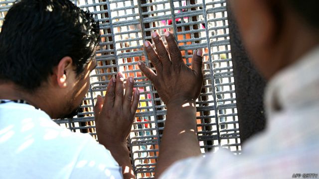 Personas a ambos lados de una valla en la frontera entre EE.UU. y México