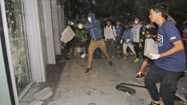 蒙面示威者用磚塊砸破香港立法會大樓的玻璃門（19/11/2014）