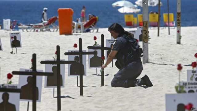 Una policía coloca flores en cruces representando policías muerto en Río.