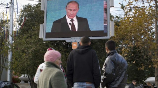 Перехожі у Севастополі дивляться на великому екрані виступ президента Росії у жовтні