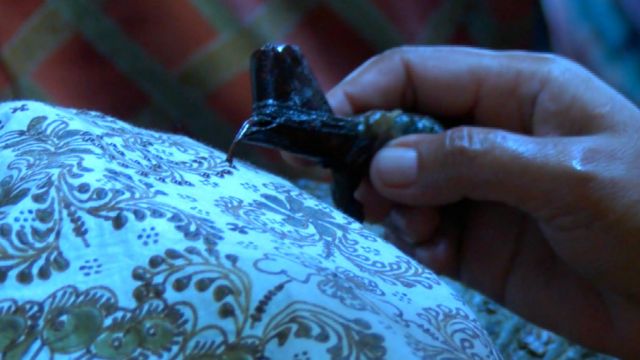 Pengrajin batik menempelkan lilin atau malam pada sehelai batik