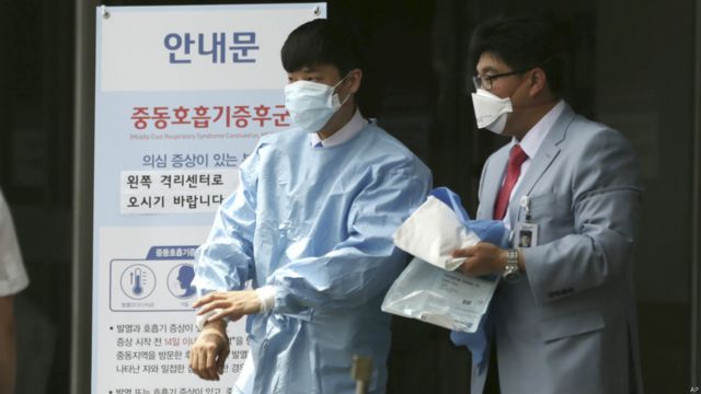 首爾國立大學附設醫院外一名醫護人員走過宣傳防範MERS病毒的告示板（2/6/2015）