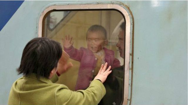 Una mujer saluda a su hijo, mientras se aleja en un tren.