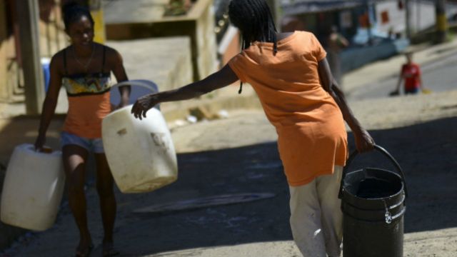 Dos mujeres cargan botes con agua en Colombia.