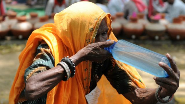 Mujer tomando agua en India