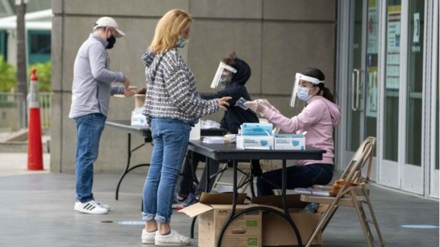 Polling place employees assist voters outside of the Staples Center as California Early Voting begins in person for the US Presidential Election, in Los Angeles, California, USA, October 24, 2020 .