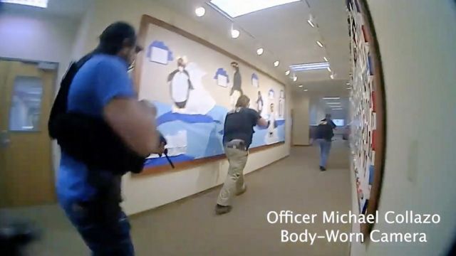 Três policiais com arma apontada correndo em fila em corredor de escola