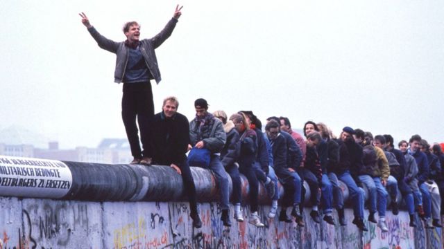 Alemães ocidentais celebram o colapso do comunismo no topo do Muro de Berlim, em 12 de novembro de 1989