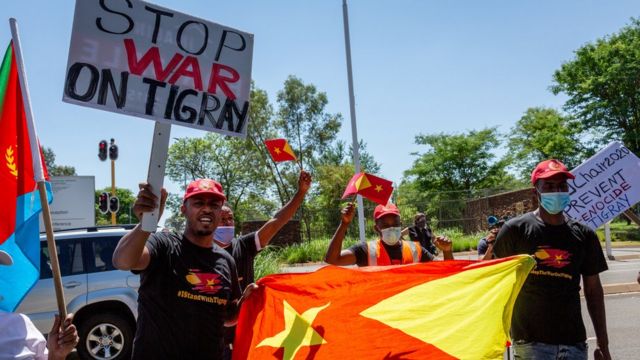Protesters hold banners showing Stop War in Tigray