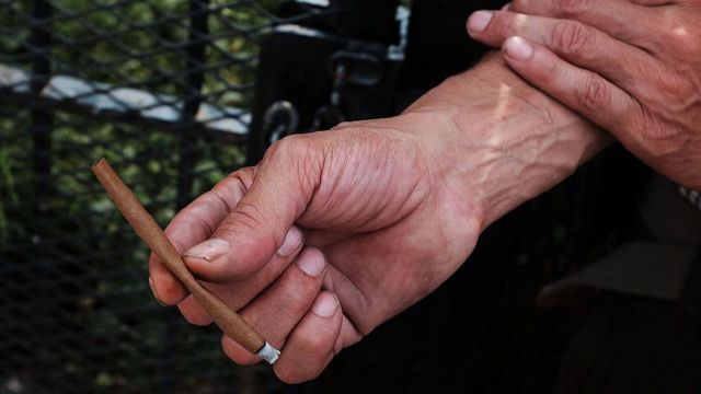 Mão de homem segura cigarro artesanal feito com k9