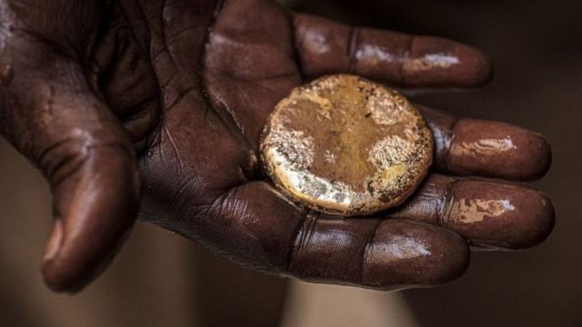 Très gros plan sur une main mouillée portant un morceau d'or