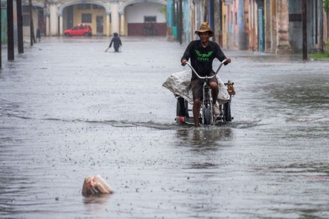 Un hombre circula en triciclo por una calle inundada en La Habana.