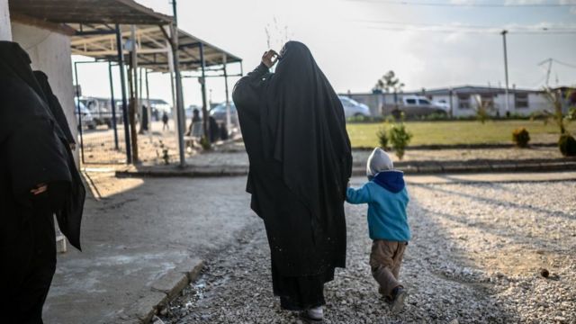 إحدى المرأتين الفرنسيتين المحتجزتين اللتين فرتا من الجيب الأخير لتنظيم الدولة الإسلامية في سوريا تمشي مع طفلها في مخيم الهول بمحافظة الحسكة شمال شرق سوريا في 17 فبراير/شباط 2019